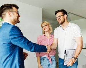 Un couple serrant la main à un agent immobilier
