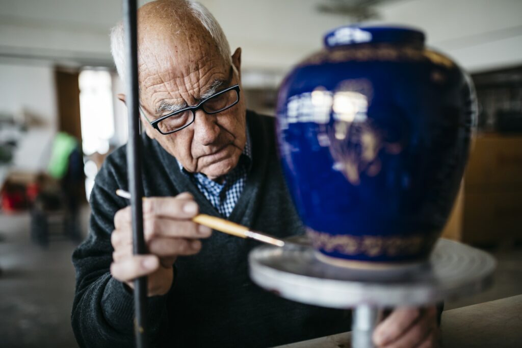 Senior man decorating ceramic vase in his spare time